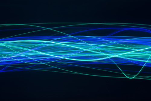 a complicated waveform pattern created from cyan and blue random and overlapping waves of light